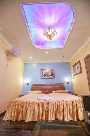 A hotel room with a bed, a ceiling light, a wall-mounted picture, and a bedside table. - Hotel Orbit Digha (Kanthi)