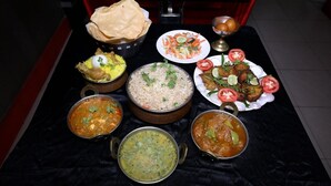 A table with various dishes including rice, curries, and a salad. - Hotel Orbit Digha (Kanthi)
