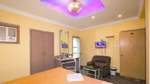 A hotel room with a bed, desk, chair, TV, wardrobe, and a ceiling light. - Hotel Orbit Digha (Kanthi)