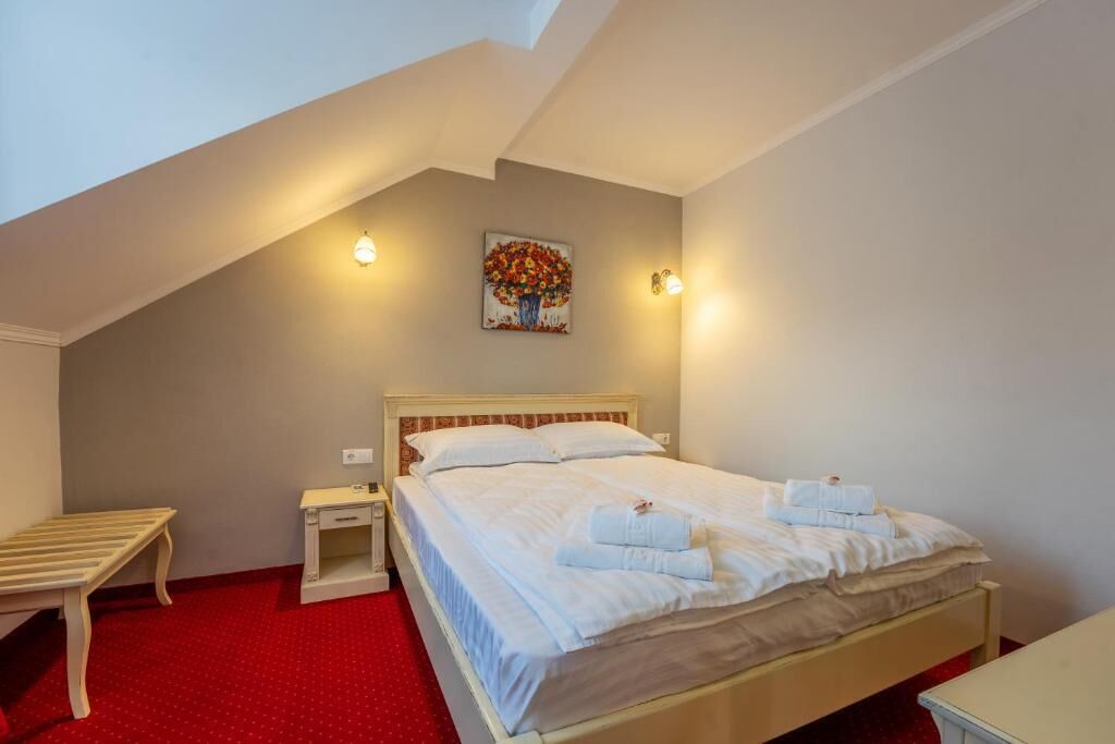 Un dormitorio con cama, mesita de noche y un cuadro en la pared.