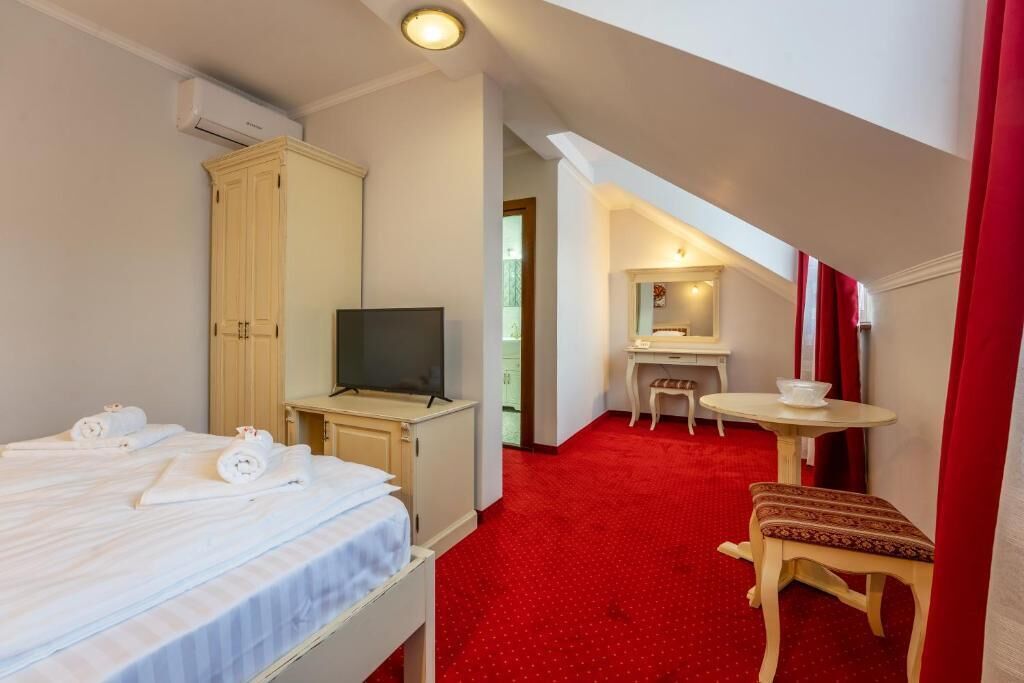 Une chambre d’hôtel comprenant un lit, un bureau, une chaise, une télévision et une armoire.
