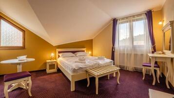 Una habitación de hotel con cama, mesita de noche, silla y una pequeña mesa con lámpara.