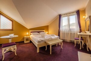Una habitación de hotel con cama, mesita de noche, silla y una pequeña mesa con lámpara.