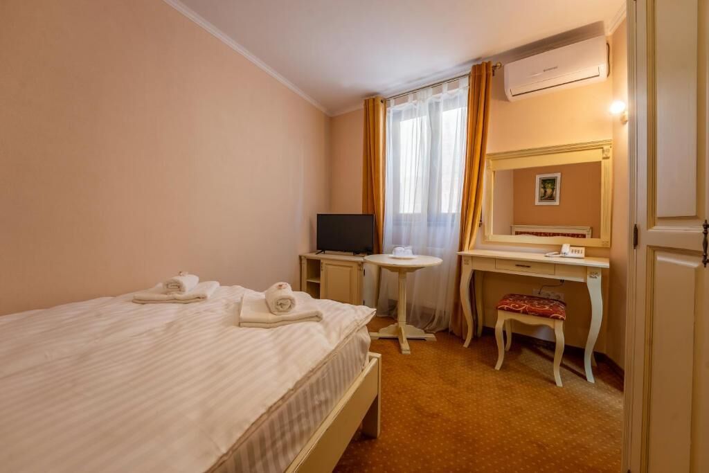 Una camera d'albergo con un letto, una scrivania, una televisione e un climatizzatore.