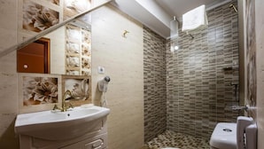 A bathroom with a white sink, a toilet, and a shower area with tiled walls. - Hotel PrincesSophie (Sighisoara)