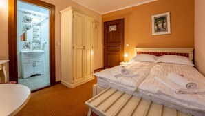 A hotel room with a bed, a bedside table, a wardrobe, and a bathroom visible through a glass door. - Hotel PrincesSophie (Sighisoara)