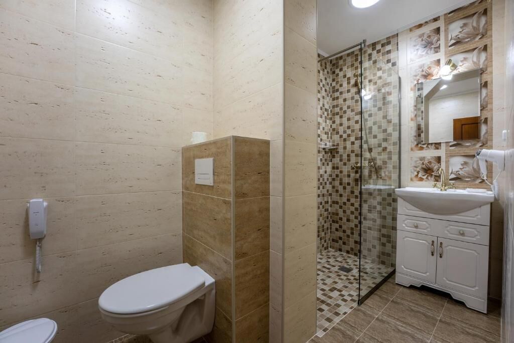 A bathroom with a toilet, a shower enclosure, and a sink with a mirror.