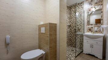 A bathroom with a toilet, a shower enclosure, and a sink with a mirror.