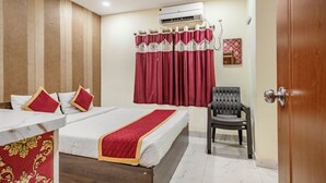 Una habitación de hotel con cama, sillón, aire acondicionado y cortina.