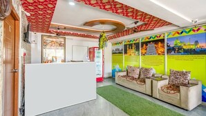 Un área de recepción con un mostrador blanco, alfombra verde y una pared con murales coloridos.
