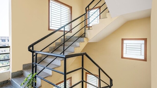 Un interior de varios niveles con una escalera, ventanas y una planta.