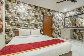 Un dormitorio con una cama, una puerta de madera, un armario y un espejo.