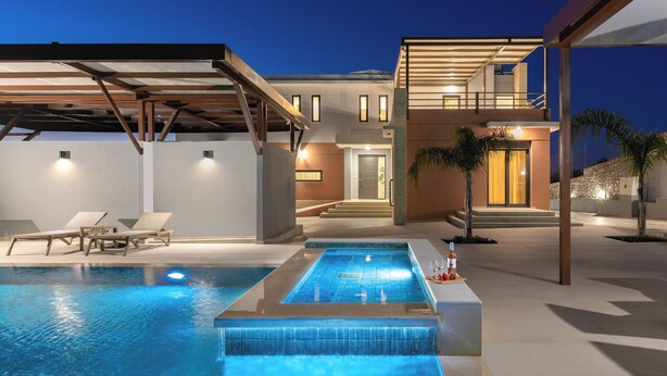 A modern pool area with lounge chairs, a hot tub, and a two-story building with a covered patio. - Elias Rest Villa with private pool (Pastida)