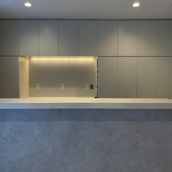 Un baño moderno y minimalista con un espejo grande, iluminación empotrada y una paleta de colores neutros.