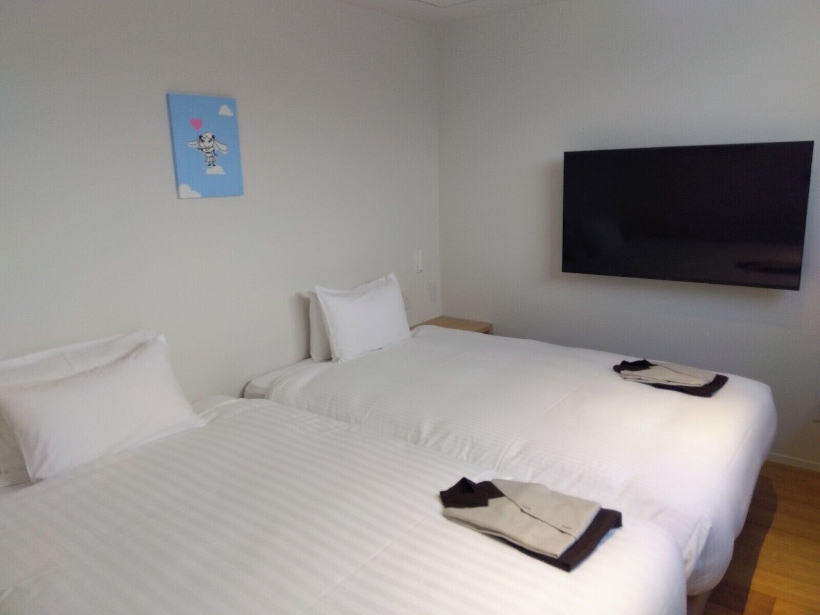 Une chambre d’hôtel avec deux lits, un téléviseur à écran plat et une œuvre d’art accrochée au mur.