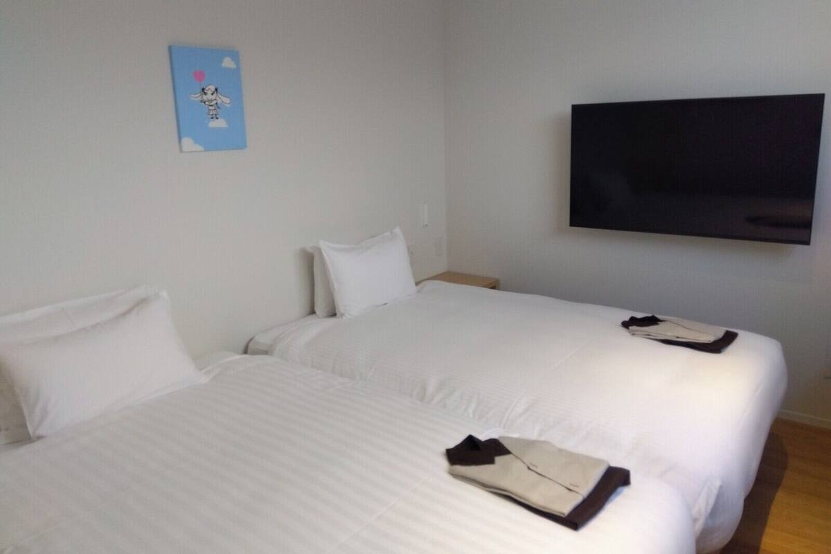 Ein Hotelzimmer mit zwei Betten, einem Flachbildfernseher und einem an der Wand befestigten Kunstwerk.