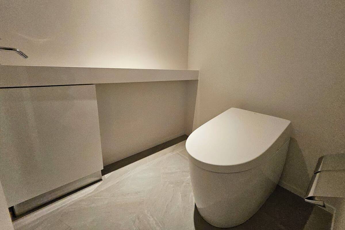 Ein modernes Badezimmer mit Toilette, Waschtisch und Duschbereich.