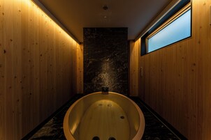 Un baño con paredes de madera, pared de mármol y una bañera grande.