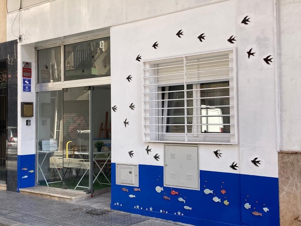 A building facade with a blue and white color scheme, a window with a grid pattern, and a sign indicating a marina.