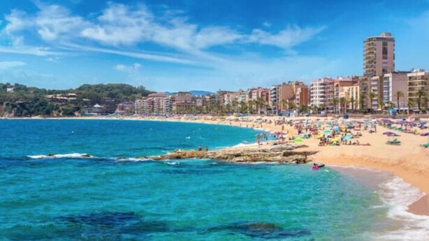 A beach with clear blue waters, a sandy shore, and buildings in the background. - Golondrinas de Malaga (Málaga)