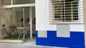A building with a glass door entrance, a window with horizontal blinds, and a blue and white facade. - Golondrinas de Malaga (Málaga)