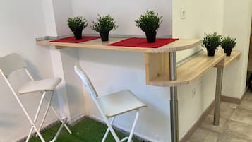 A small room with a wooden desk, two white chairs, and artificial green grass flooring.