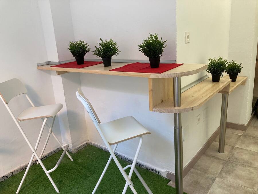 A small room with a wooden desk, two white chairs, and artificial green grass flooring.