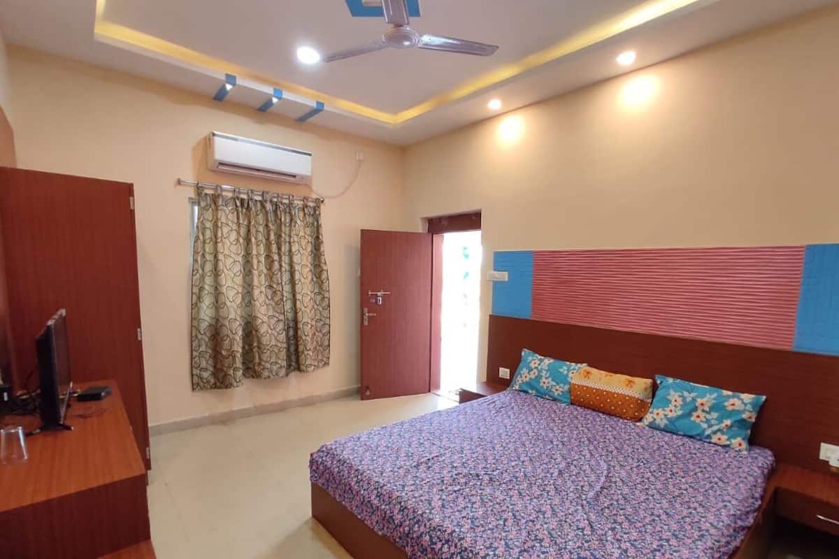 Un dormitorio con cama, escritorio, aire acondicionado y ventilador de techo.