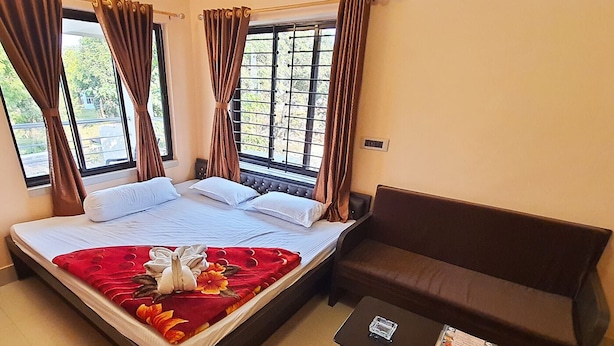 A hotel room with a bed, a brown sofa, and a small table with a menu.