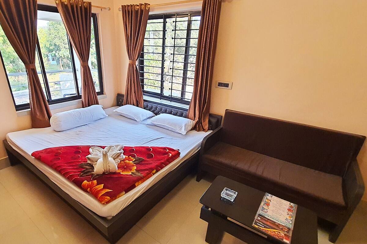 Una habitación de hotel con una cama, un sofá marrón y una mesita con un menú.