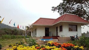 A single-story house with a red roof, a front porch, and a small garden with marigold flowers.