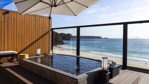 A hot tub with a wooden deck, a wooden wall, and a view of the beach and ocean. - izukaorukaze (Shimoda)
