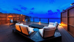 A deck with outdoor seating and a view of the ocean at dusk. - izukaorukaze (Shimoda)