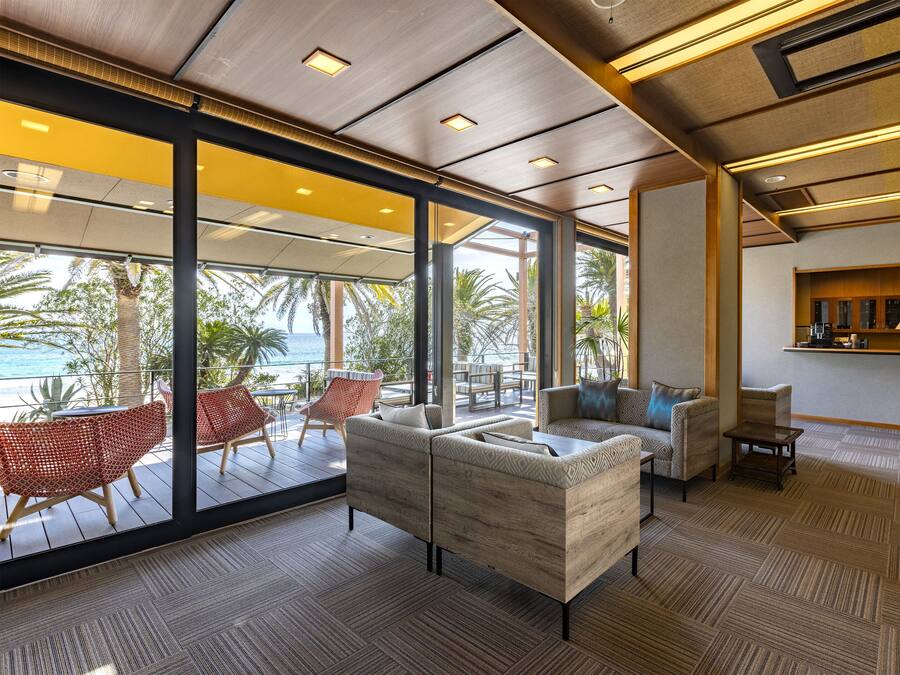 A modern lounge with a view of the ocean, featuring a sofa, chairs, and a small table.