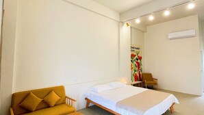 Una stanza con un letto, una poltrona, una panca in legno e una sedia.
