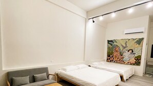 Una camera da letto moderna con un divano, due letti singoli, una panca in legno e cuscini decorativi.