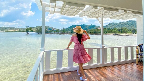 A covered outdoor area with a wooden deck, overlooking a body of water and a hilly landscape. - Morelo Water Villa (Galang)