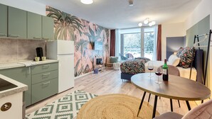 A modern kitchen with green cabinets, a coffee machine, and a dining area with a round table and chairs. - Apartment Rio (Winterberg)
