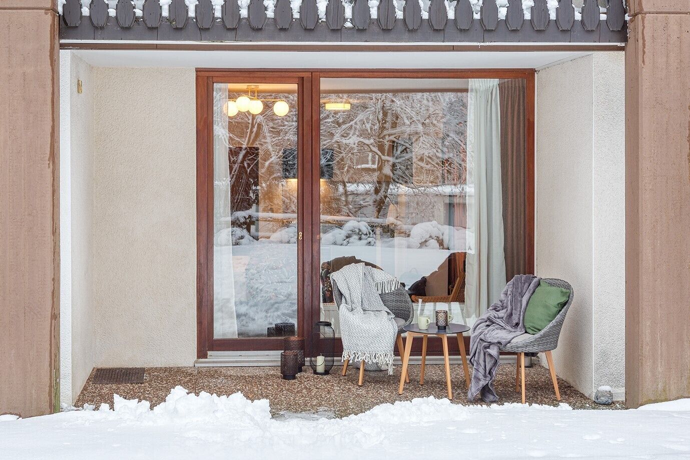 Une pièce confortable avec une grande fenêtre, un fauteuil, une petite table et une porte.