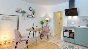 A modern kitchen with a built-in oven, a dining area with two chairs and a table, and a small round rug. - Apartment Rio (Winterberg)