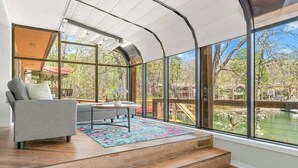 A spacious room with a curved ceiling, large windows, a wooden floor, a gray sofa, and a small table.