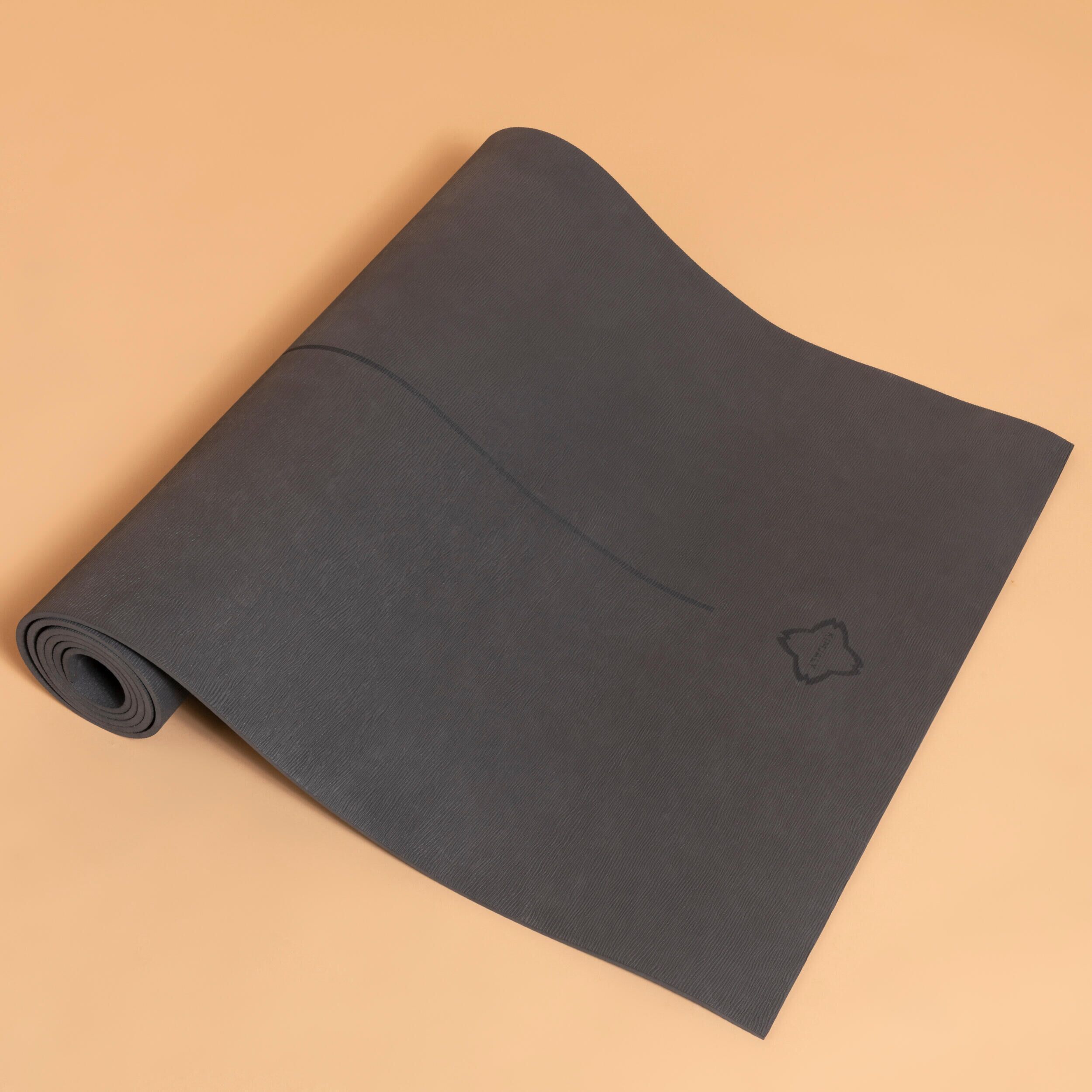 A rolled yoga mat on a plain surface.