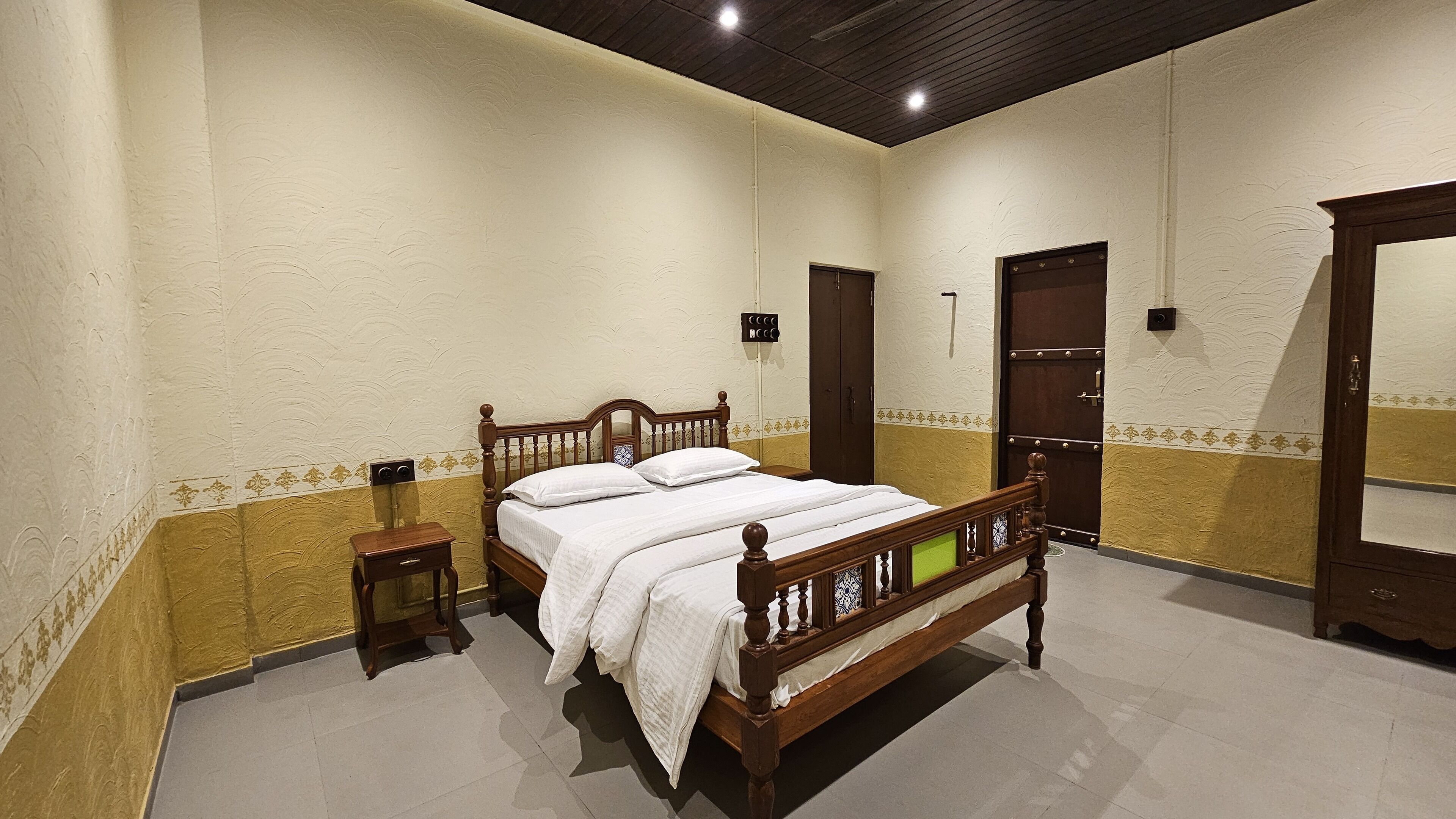 A bedroom with a wooden bed, a nightstand, a wardrobe, and a mirror.