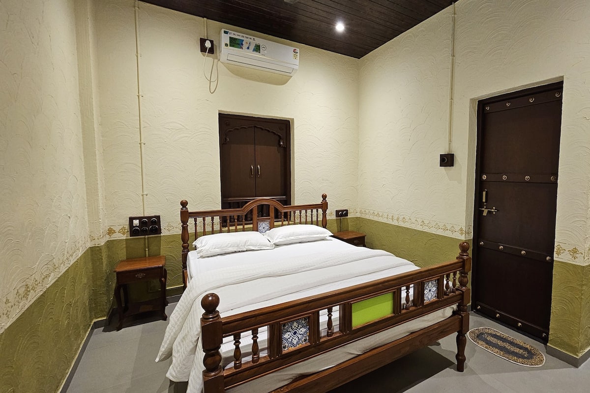 Quarto com cama de madeira, guarda-roupa, mesa de cabeceira e porta.