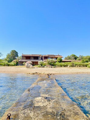 A traditional building with a tiled roof, situated by a clear water body.