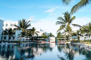 A pool area with lounge chairs, umbrellas, and palm trees. - Agarwood Villa - Beach and Pool Phu Quoc (Phu Quoc)