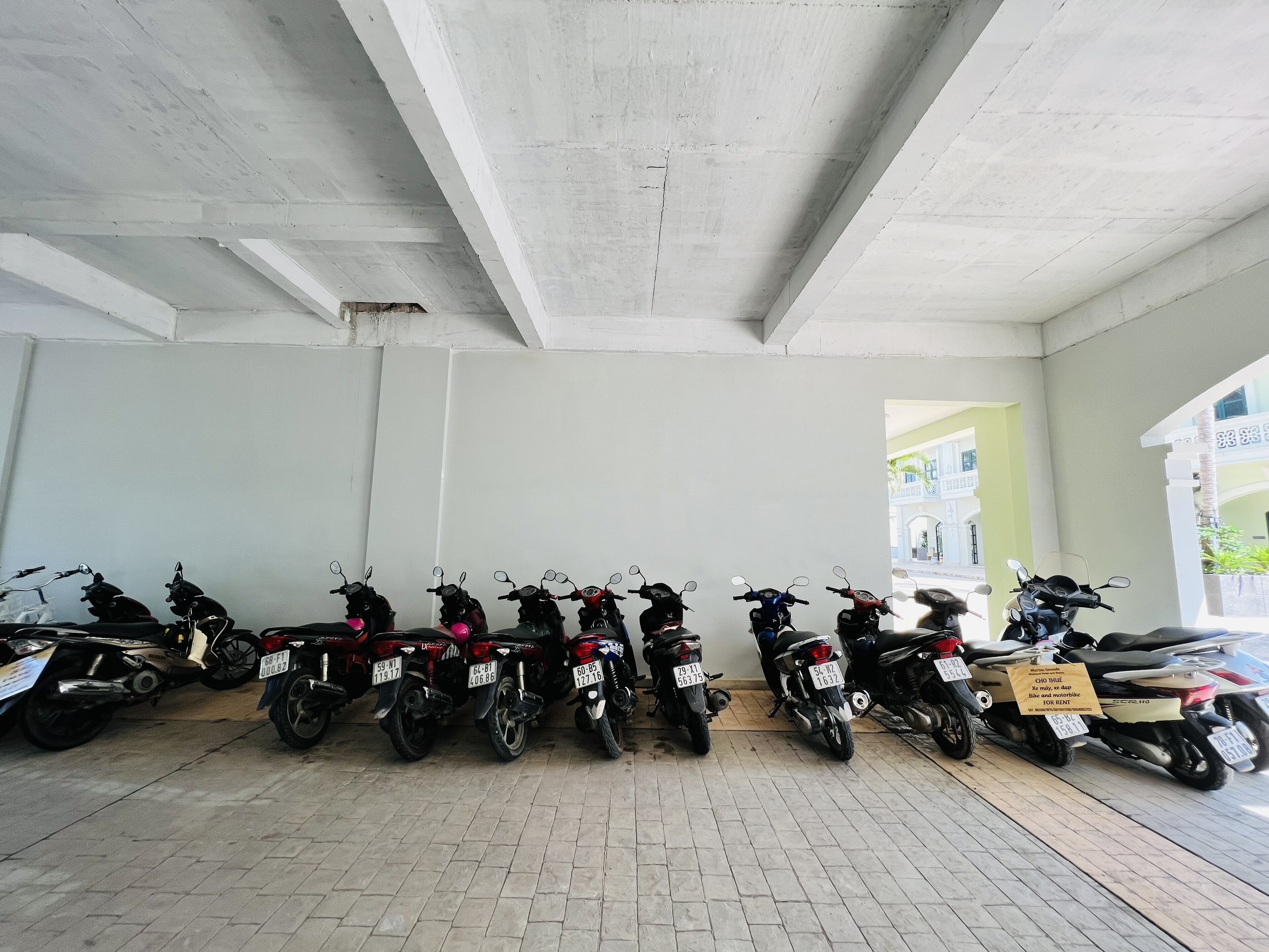 Un área de estacionamiento con varias motocicletas alineadas contra una pared.