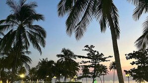 A poolside area with palm trees, a view of the sea, and people dining at tables. - Agarwood Villa - Beach and Pool Phu Quoc (Phu Quoc)