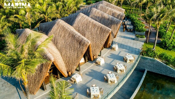 A resort with thatched-roof structures and outdoor seating by a pool. - Agarwood Villa - Beach and Pool Phu Quoc (Phu Quoc)
