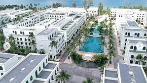 A resort with multiple white buildings, a central swimming pool, and palm trees. - Agarwood Villa - Beach and Pool Phu Quoc (Phu Quoc)